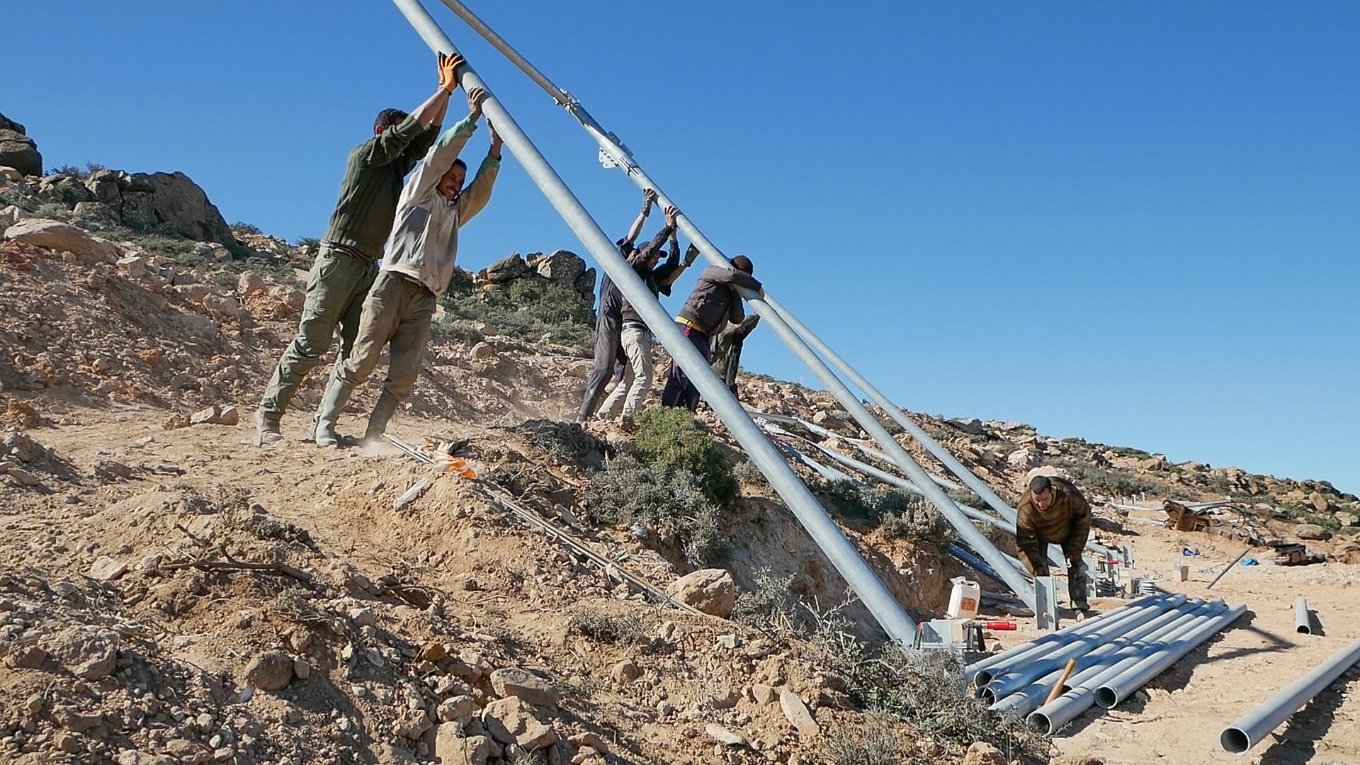 8/17:The combined efforts of the entire team are required to attach the heavy steel posts of the collector frames to the ground anchors. Everyone pitches in with enthusiasm. 8/17:The combined efforts of the entire team are required to attach the heavy steel posts of the collector frames to the ground anchors. Everyone pitches in with enthusiasm.