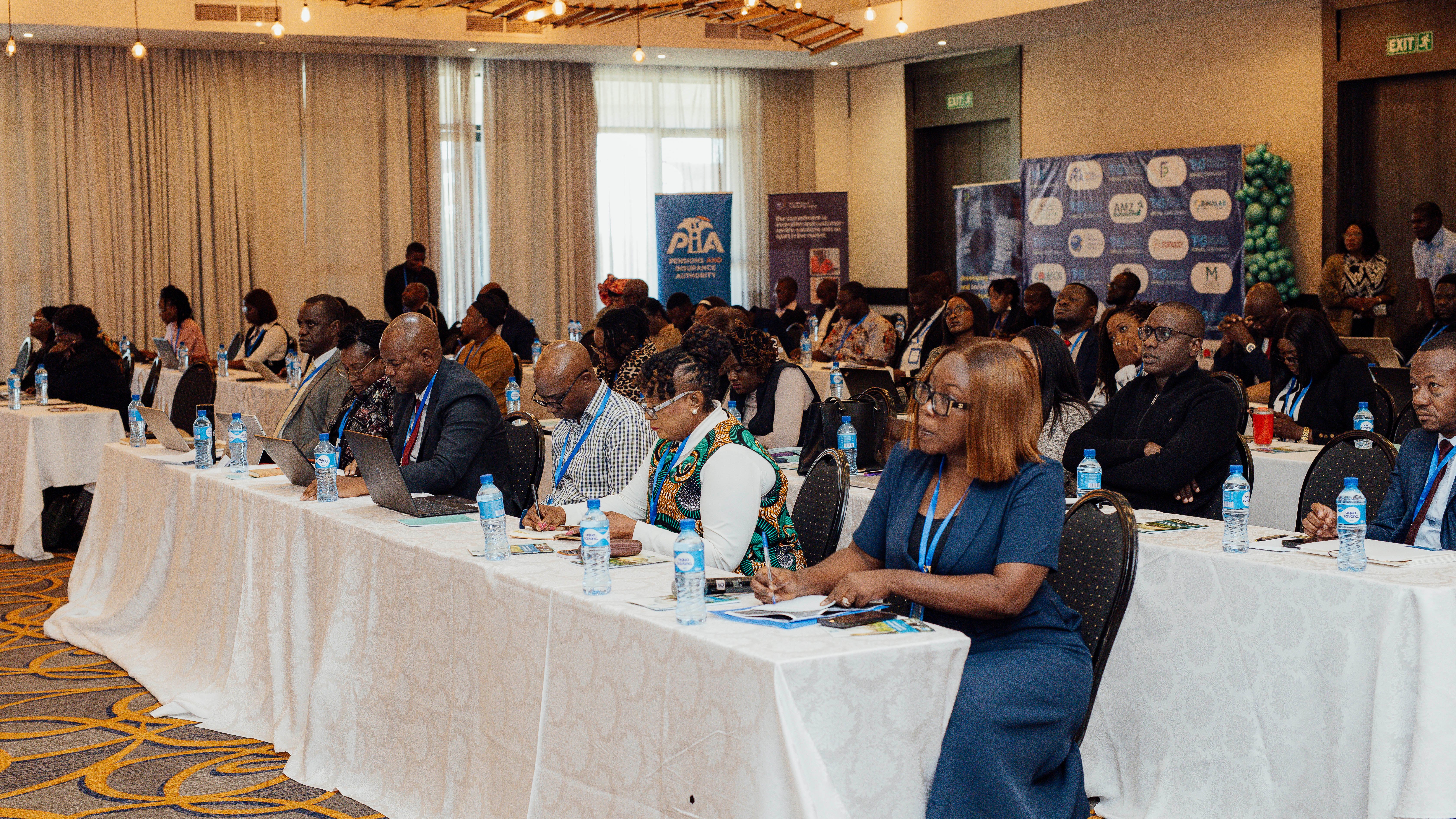 A conference room filled with attendees seated at tables, engaged in a presentation.