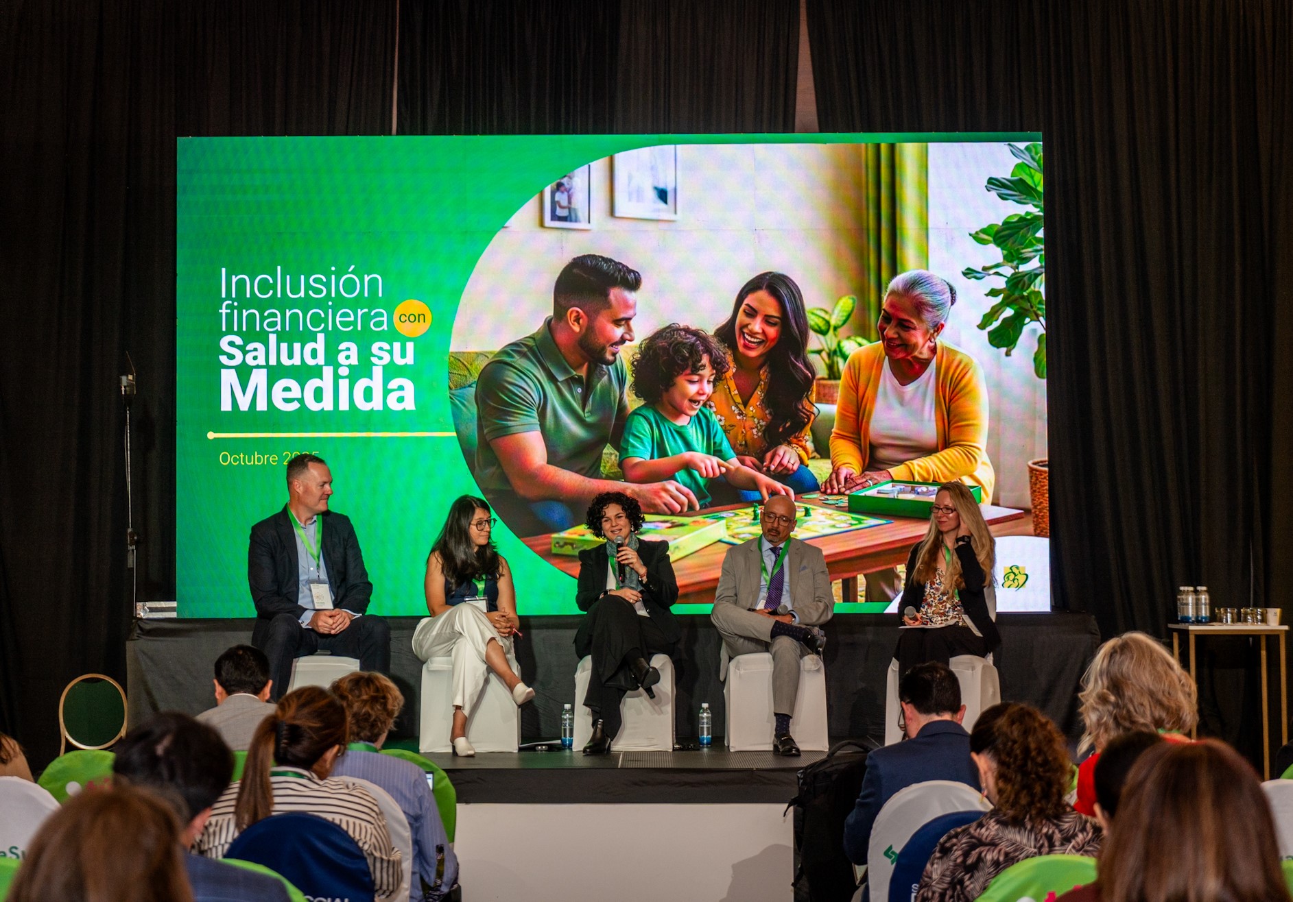 Panel discussion with speakers in front of a large screen displaying a family interacting.