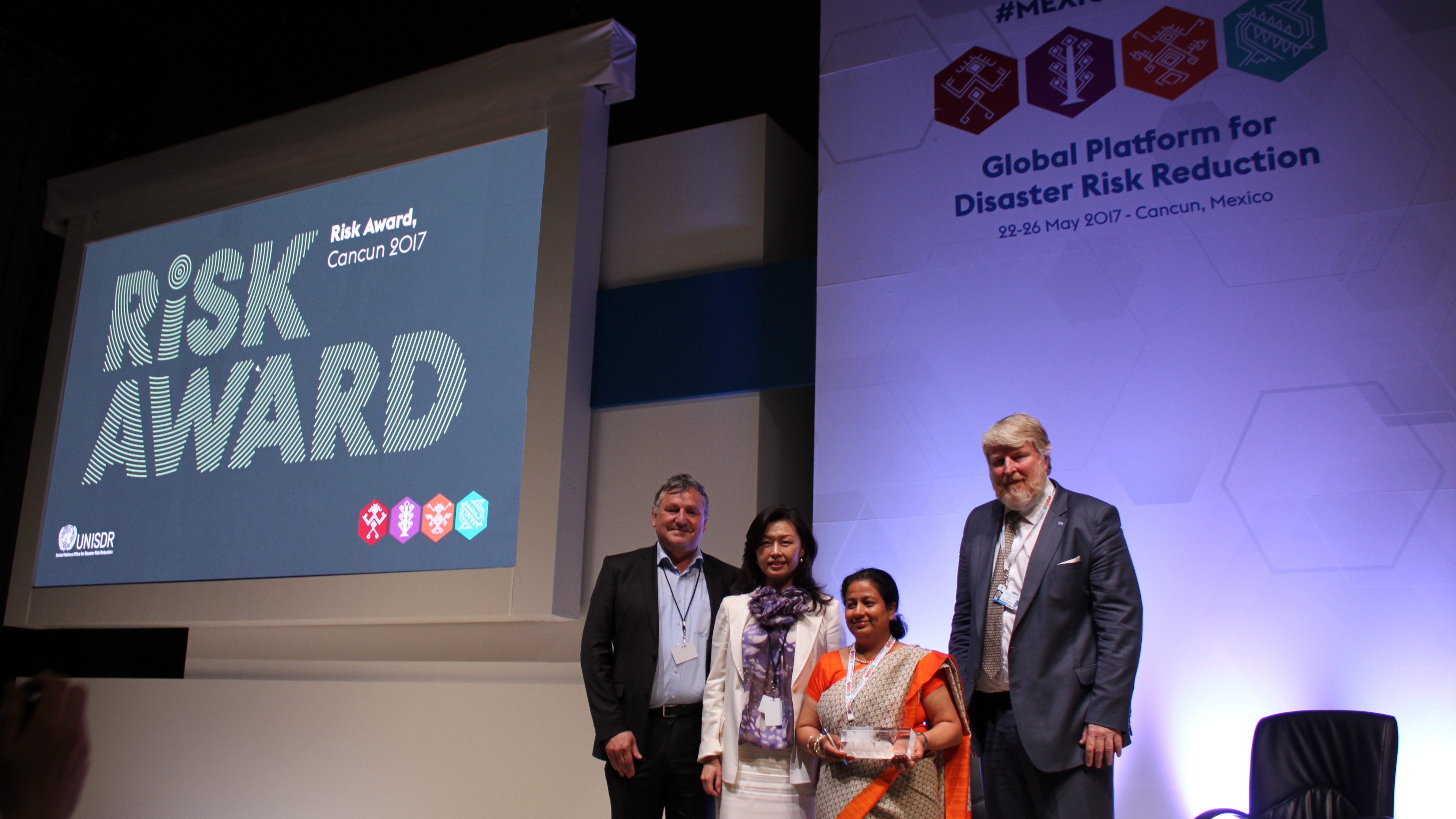 Thomas Loster (Munich Re Foundation) and Sandra Wu (RISK Award jury member) handed over the trophy to Apsara Pandey. The session was hosted by UNISDR, represented by David Stevens (right).