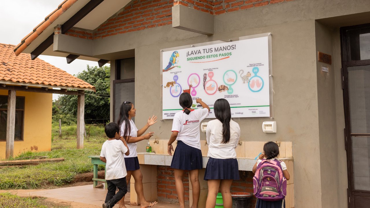 5 children look at the poster in front of the rehabilitated school bathrooms in Monte Verde