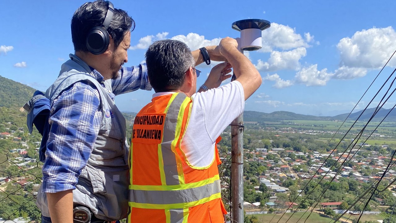 Two men installing a raingauge in Villanueva